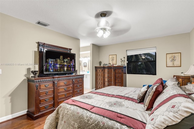 bedroom with connected bathroom, hardwood / wood-style flooring, and ceiling fan