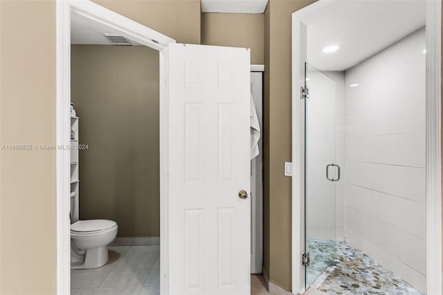 bathroom featuring tile patterned flooring, a textured ceiling, toilet, and an enclosed shower