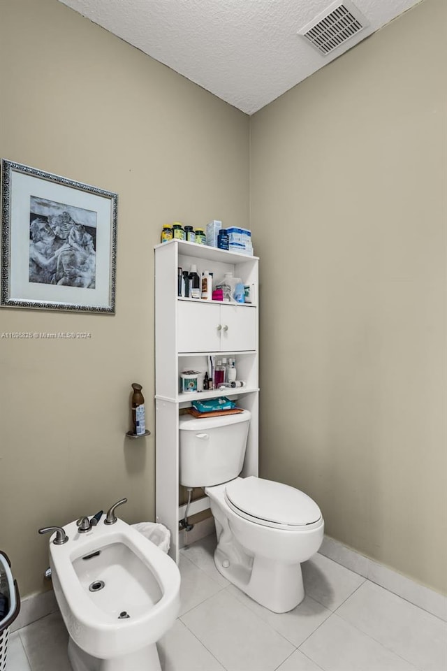 bathroom featuring toilet, a textured ceiling, tile patterned floors, and a bidet