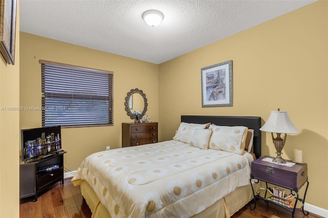 bedroom with a textured ceiling and dark hardwood / wood-style floors