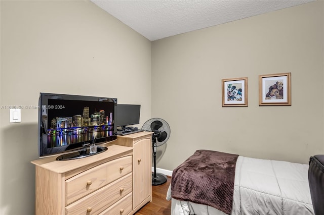 bedroom featuring vaulted ceiling, light hardwood / wood-style floors, and a textured ceiling