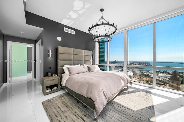 bedroom featuring a chandelier, light tile patterned floors, and a water view