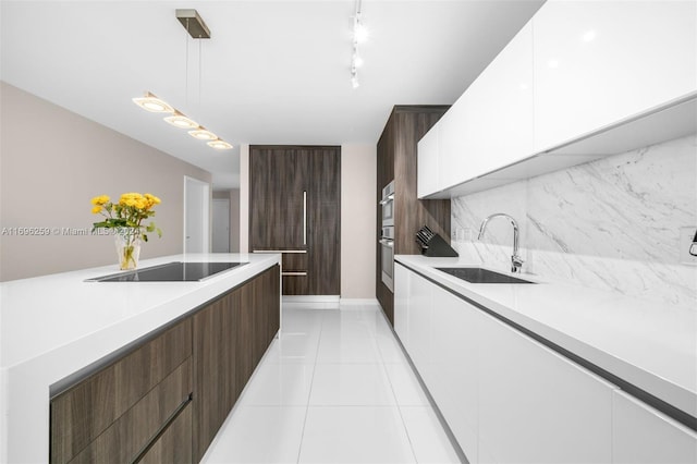 kitchen with black electric stovetop, sink, pendant lighting, light tile patterned floors, and white cabinetry