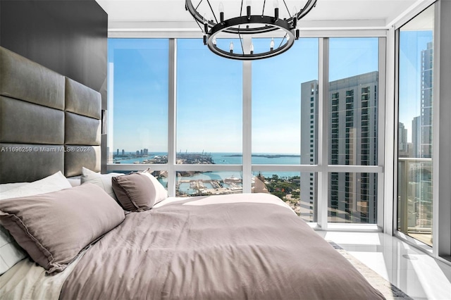 unfurnished bedroom featuring an inviting chandelier, a water view, and multiple windows