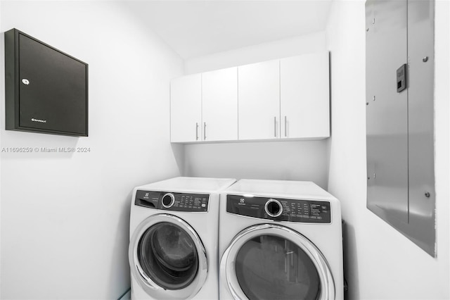 clothes washing area with cabinets and washing machine and dryer