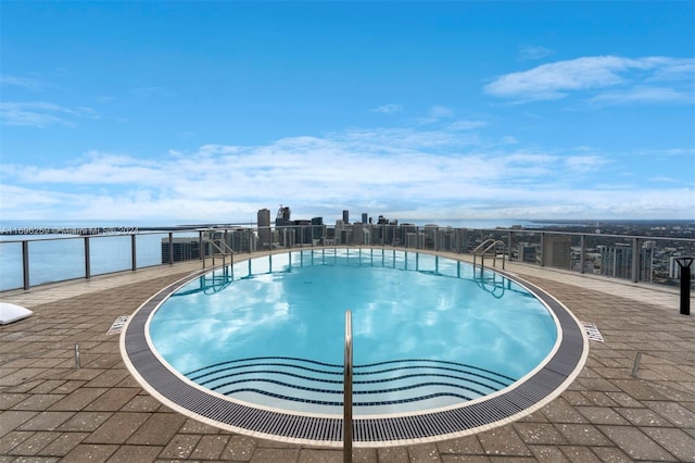 view of swimming pool featuring a patio and a water view