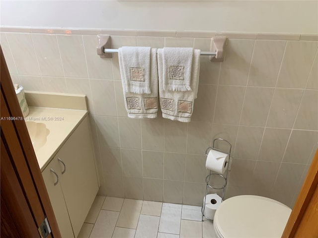 bathroom with tile patterned floors, vanity, toilet, and tile walls