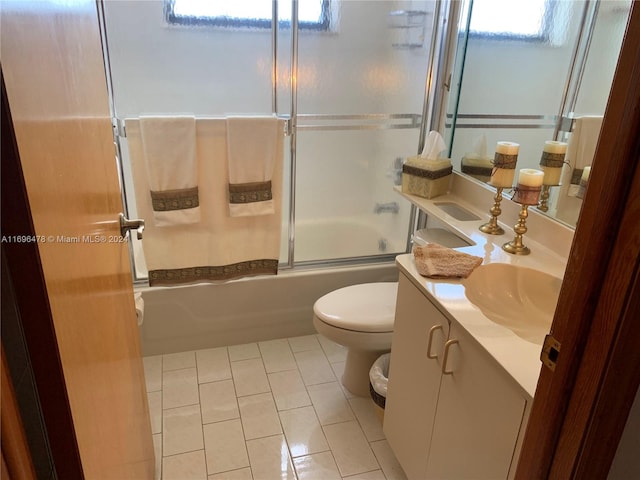 full bathroom featuring tile patterned flooring, vanity, a healthy amount of sunlight, and combined bath / shower with glass door