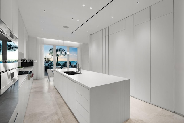 kitchen with white cabinets, a center island with sink, and sink