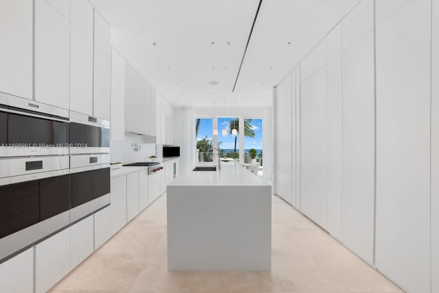 kitchen with white cabinetry, sink, a kitchen island, and stainless steel gas cooktop