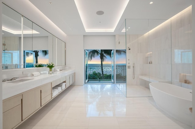 bathroom with a raised ceiling, vanity, tile patterned flooring, and plus walk in shower