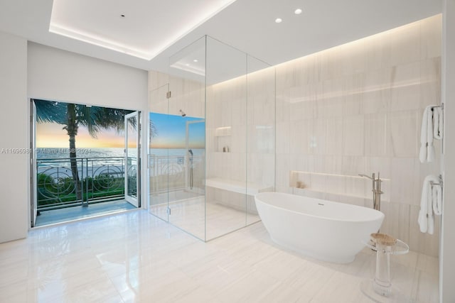 bathroom with tile walls, plus walk in shower, and a tray ceiling