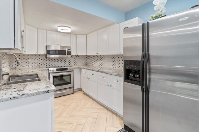 kitchen featuring appliances with stainless steel finishes, white cabinetry, and sink