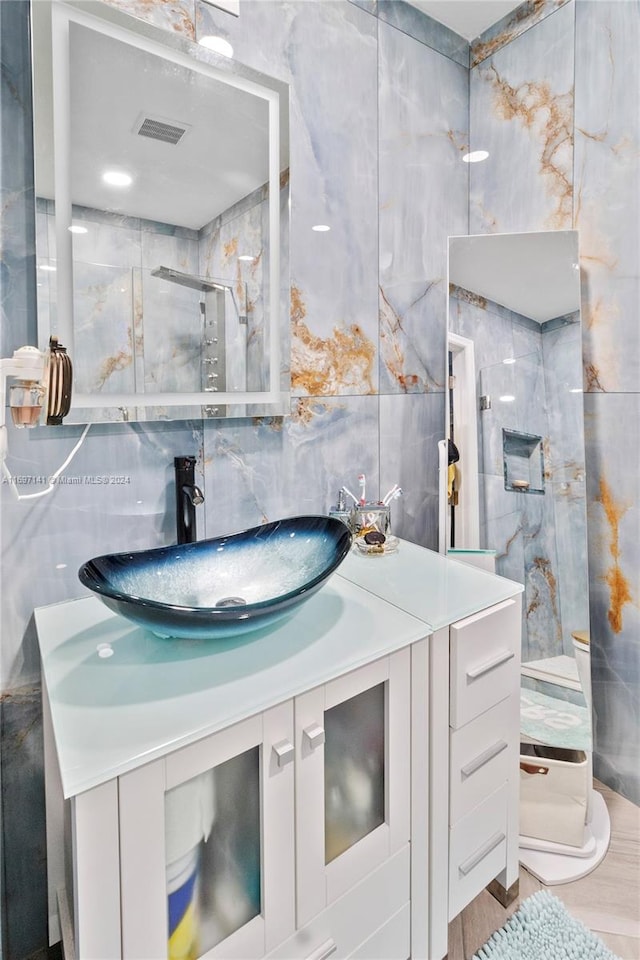 bathroom featuring a shower with door, vanity, hardwood / wood-style floors, and tile walls