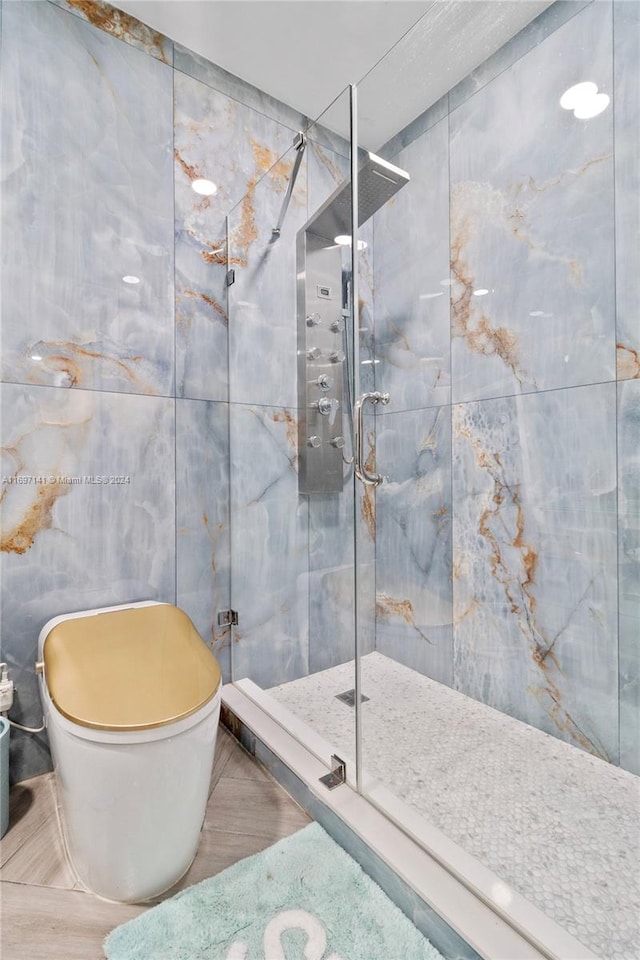 bathroom with tile patterned floors, a shower with shower door, tile walls, and toilet