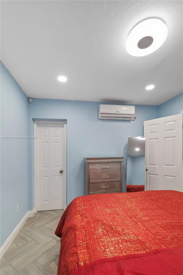 bedroom featuring a textured ceiling, light parquet flooring, and a wall mounted AC