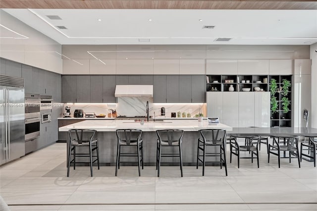 kitchen with gray cabinets, appliances with stainless steel finishes, tasteful backsplash, a large island, and a breakfast bar area