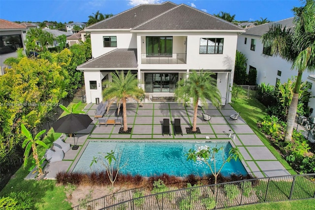 rear view of house with an outdoor living space, a patio area, a balcony, and a fenced in pool