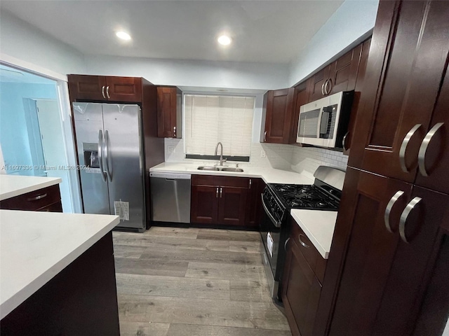 kitchen featuring decorative backsplash, light wood-type flooring, stainless steel appliances, and sink