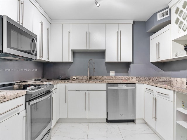 kitchen featuring sink, track lighting, stainless steel appliances, light stone countertops, and white cabinets