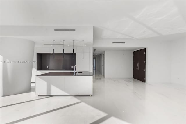 kitchen featuring white cabinets, decorative light fixtures, and sink