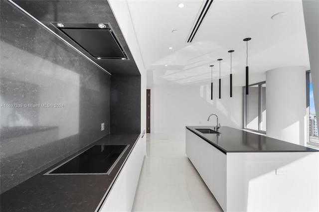 kitchen with a center island, white cabinets, sink, black stovetop, and decorative light fixtures