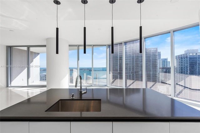 kitchen with white cabinets, a water view, sink, and hanging light fixtures