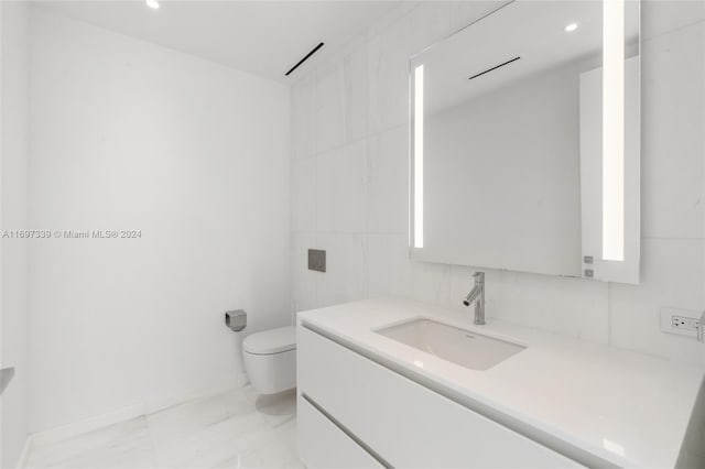 bathroom featuring vanity, tile walls, and toilet