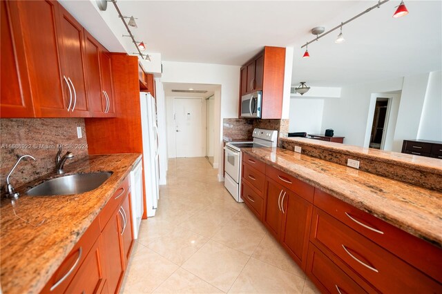 kitchen featuring white appliances, backsplash, light stone counters, and sink