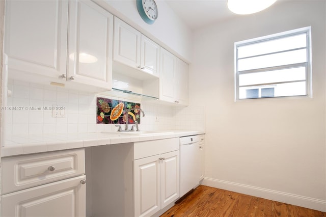 kitchen featuring tile counters, tasteful backsplash, white dishwasher, light hardwood / wood-style floors, and white cabinets