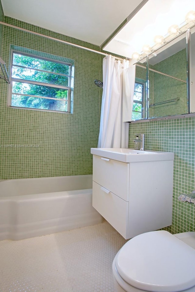 full bathroom with vanity, a healthy amount of sunlight, tile walls, and shower / tub combo