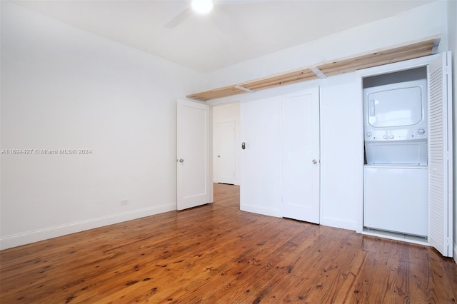 unfurnished bedroom with ceiling fan, dark hardwood / wood-style flooring, and stacked washer / drying machine