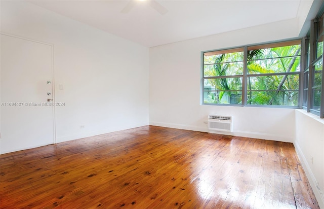 unfurnished room with a wall mounted air conditioner, hardwood / wood-style flooring, plenty of natural light, and ceiling fan