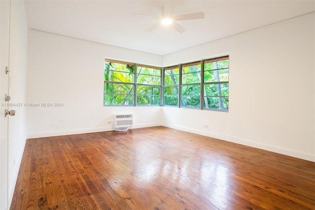 unfurnished room featuring a wall mounted air conditioner, ceiling fan, a healthy amount of sunlight, and wood-type flooring