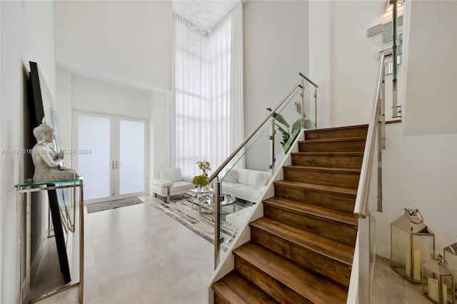 staircase featuring a towering ceiling and french doors