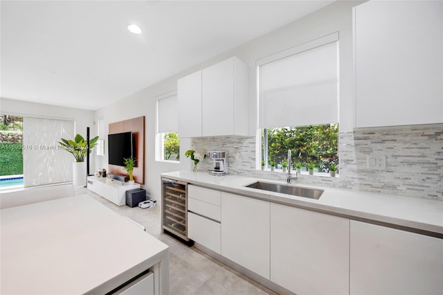 kitchen with white cabinets, tasteful backsplash, wine cooler, and sink