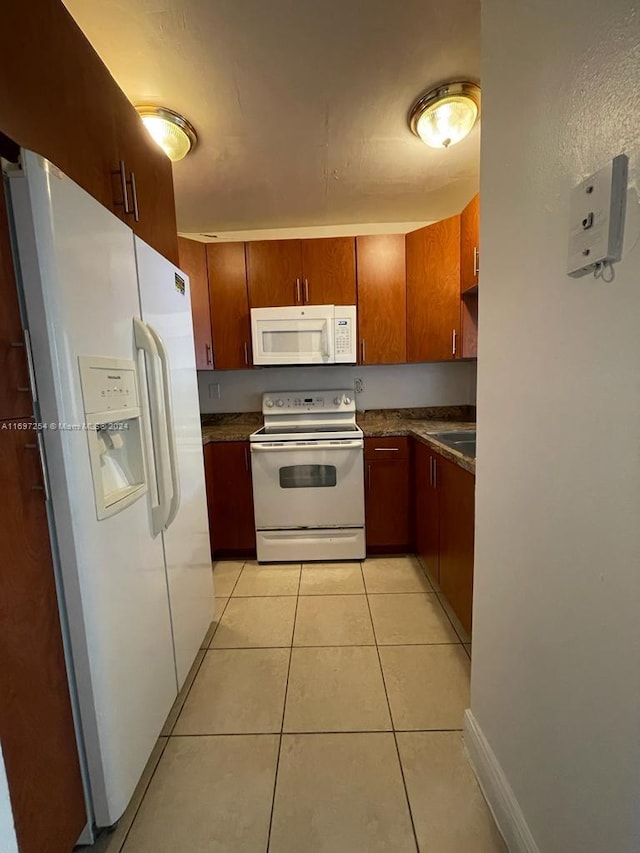 kitchen featuring light tile patterned flooring, white appliances, and sink