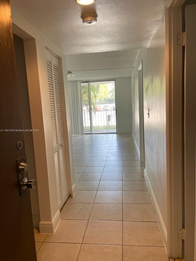 hallway featuring light tile patterned flooring and a textured ceiling