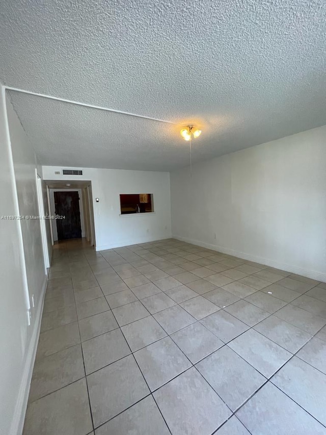 spare room featuring light tile patterned flooring and a textured ceiling