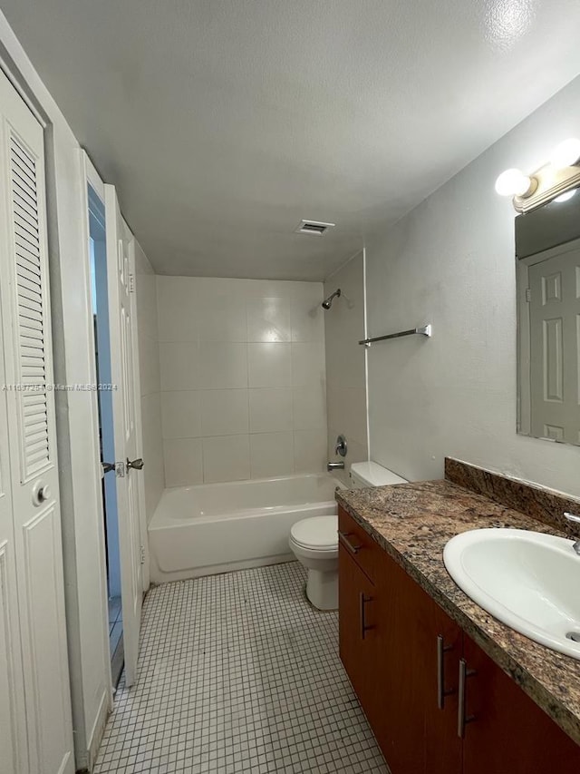 full bathroom featuring tile patterned floors, a textured ceiling, toilet, vanity, and tiled shower / bath