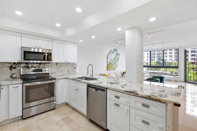 kitchen with kitchen peninsula, rail lighting, stainless steel appliances, sink, and white cabinets