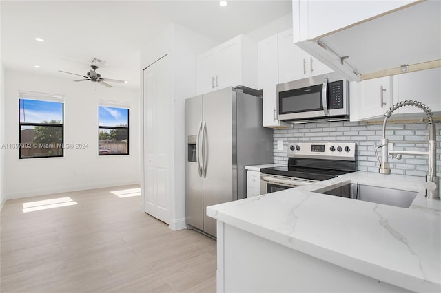 kitchen featuring light stone countertops, appliances with stainless steel finishes, light wood-type flooring, ceiling fan, and white cabinets