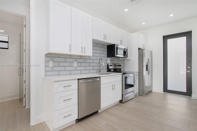 kitchen featuring light stone countertops, appliances with stainless steel finishes, light wood-type flooring, sink, and white cabinets