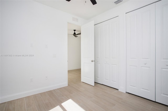 unfurnished bedroom featuring ceiling fan, light wood-type flooring, and multiple closets