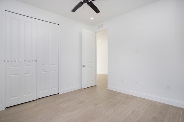 unfurnished bedroom featuring ceiling fan, light hardwood / wood-style floors, and a closet