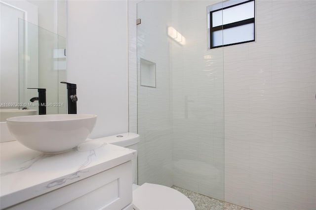 bathroom with vanity, toilet, and tiled shower