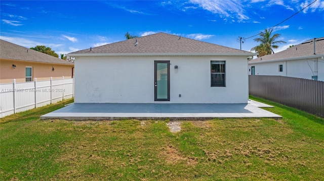 rear view of house featuring a lawn and a patio