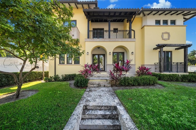 mediterranean / spanish home with a pergola, a balcony, and a front lawn