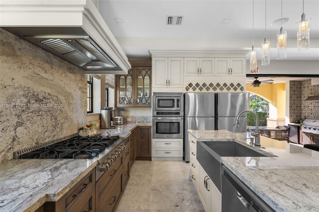 kitchen featuring light stone countertops, premium range hood, appliances with stainless steel finishes, and white cabinets