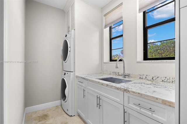 laundry area with sink, cabinets, and stacked washer and dryer